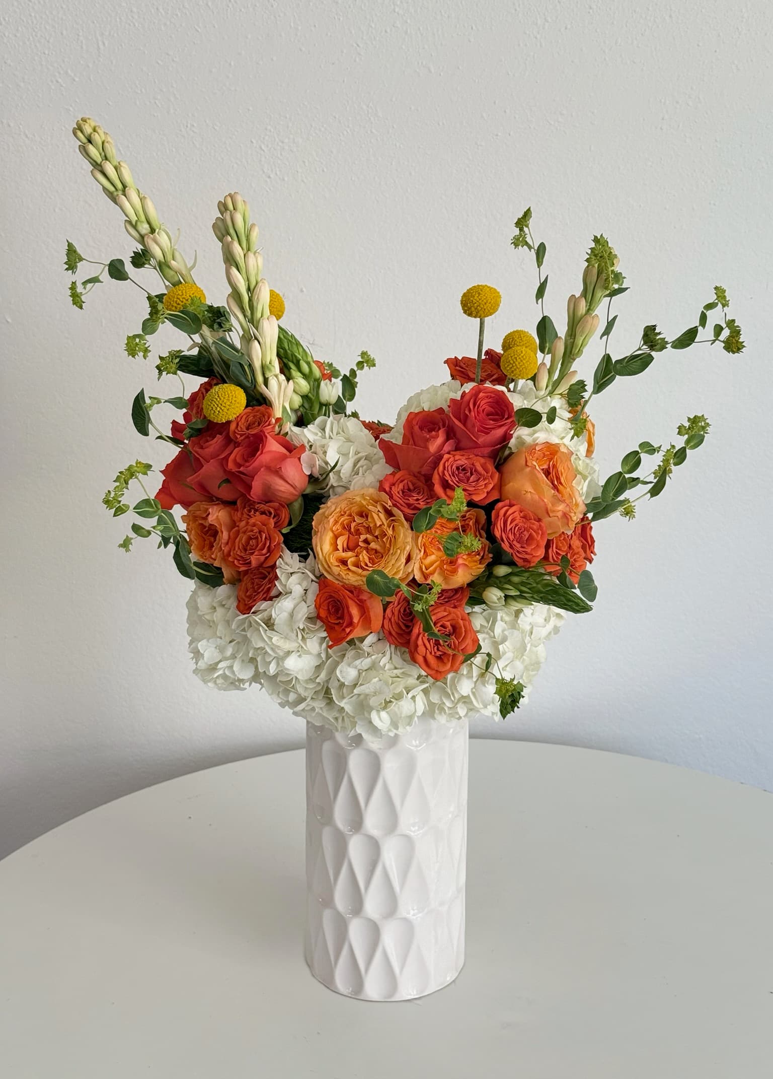 Orange Rose arrangement in a white ceramic vase